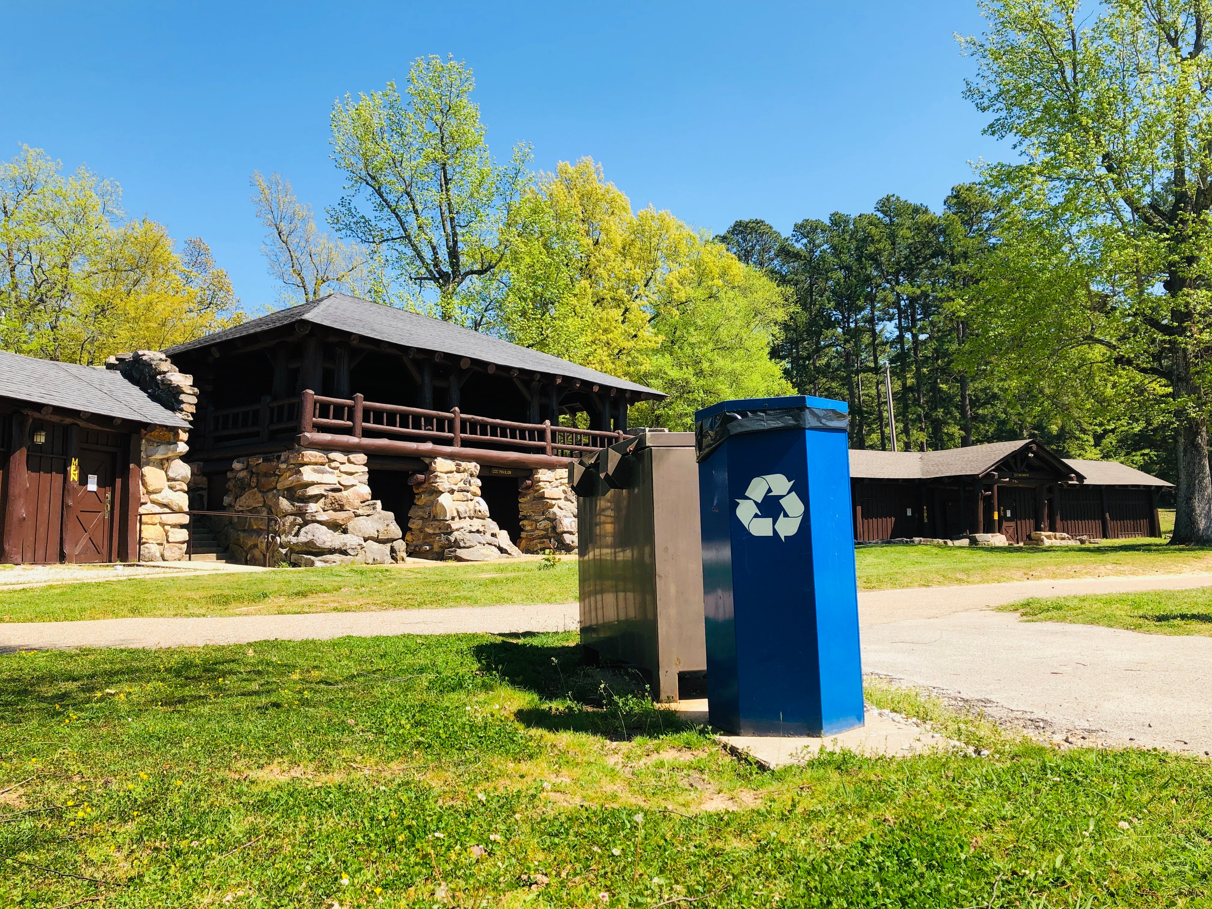 Blue, metal recycling bin in the foreground with the historic CCC pavilion in the background 
